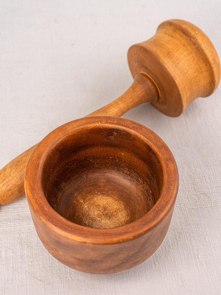 Antique French wooden mortar and pestle in turned hardwood on light textured surface, perfect for Provençal pistou.