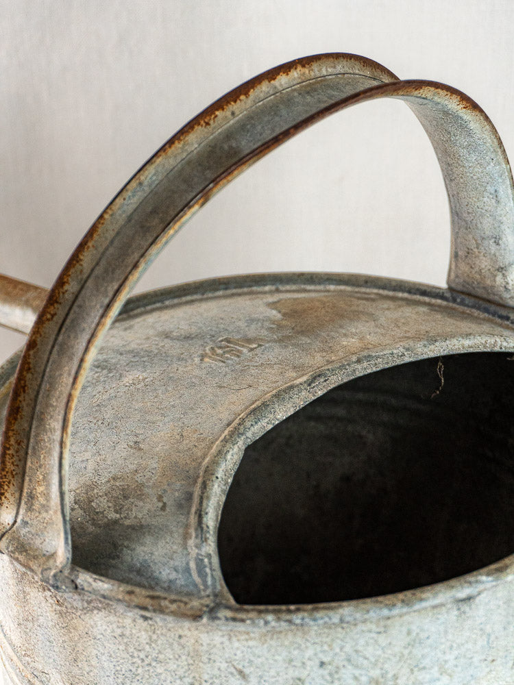 French zinc arrosoir watering can with open spout, curved handles, and weathered textured finish.